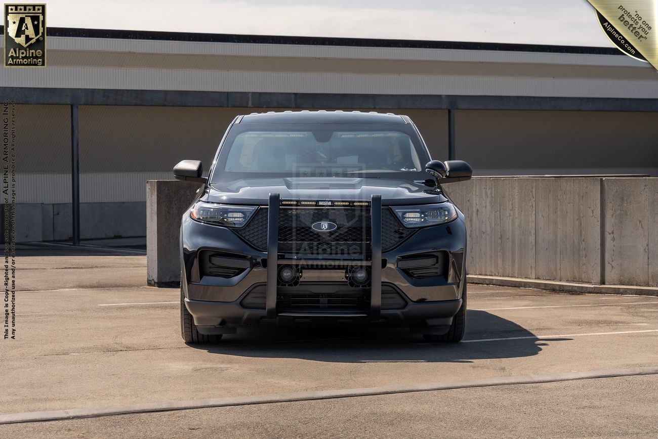 A black Ford Explorer PPV with a grille guard is parked in a rooftop parking area near a concrete barrier.