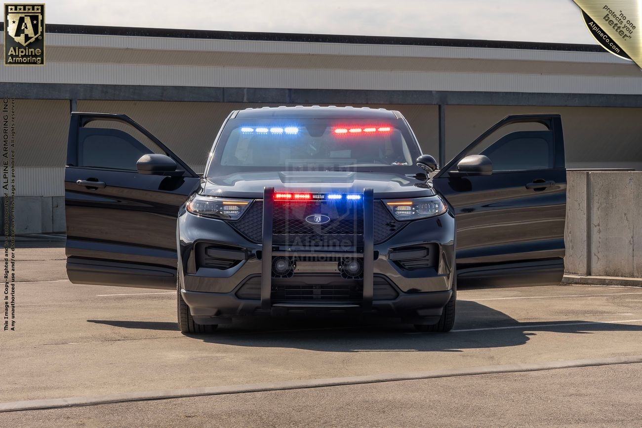 A black Ford Explorer PPV with red and blue lights flashing is parked with both front doors open. The scene appears to be on a rooftop parking lot.