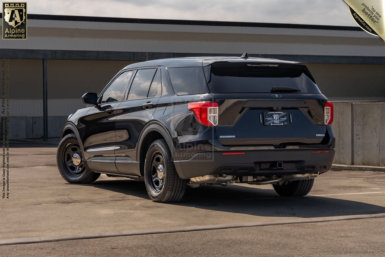 A black Ford Explorer PPV is parked in an outdoor area with a concrete wall and building in the background. The vehicle features a sleek design with tinted windows.