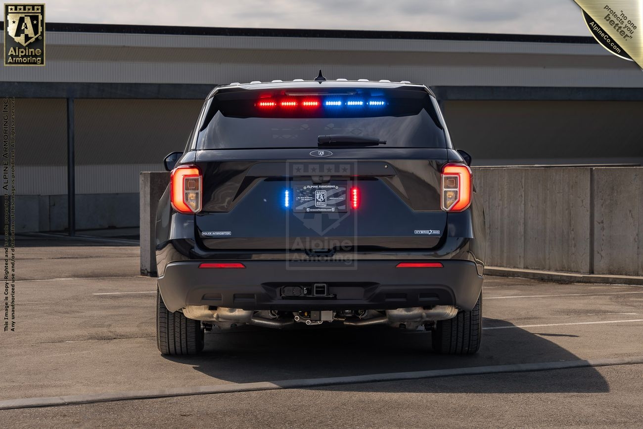 A Ford Explorer Police Protection Vehicle (PPV) with flashing red and blue lights is parked in a rooftop parking structure.