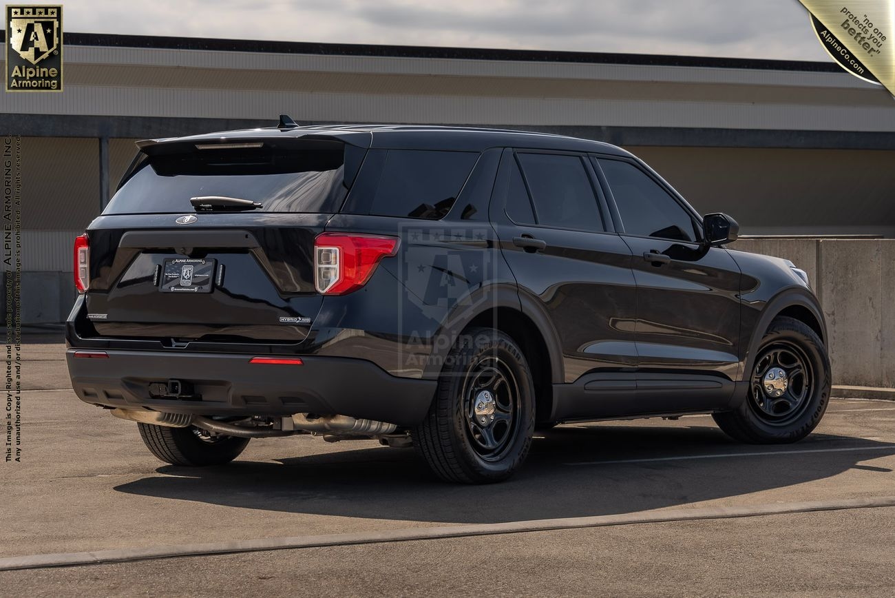 A black Ford Explorer PPV is parked in an outdoor area, facing away from the viewer. The vehicle has tinted windows and is on a concrete surface with a building in the background.