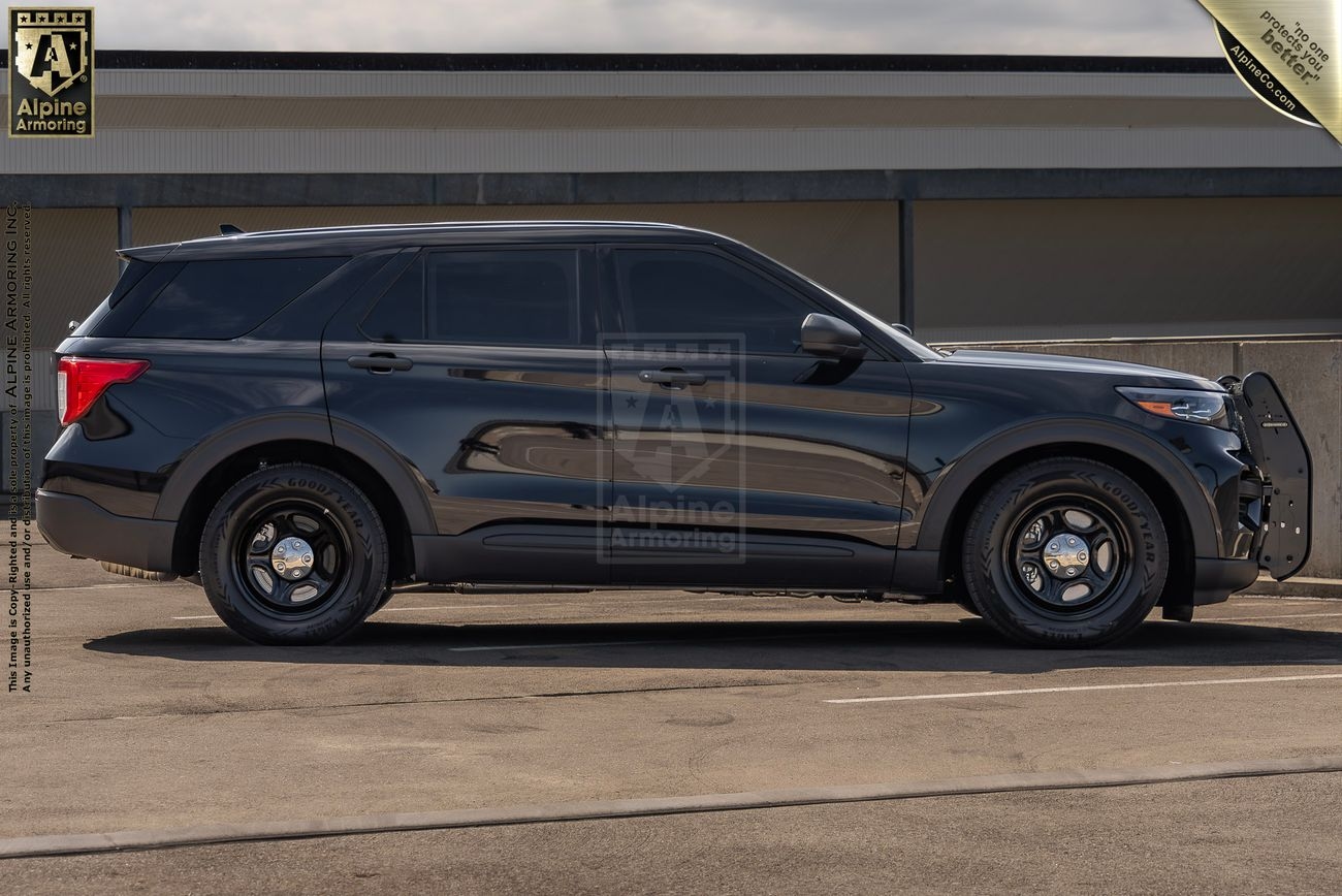 Side view of a black police Ford Explorer SUV parked on a concrete surface, with police equipment and markings visible.