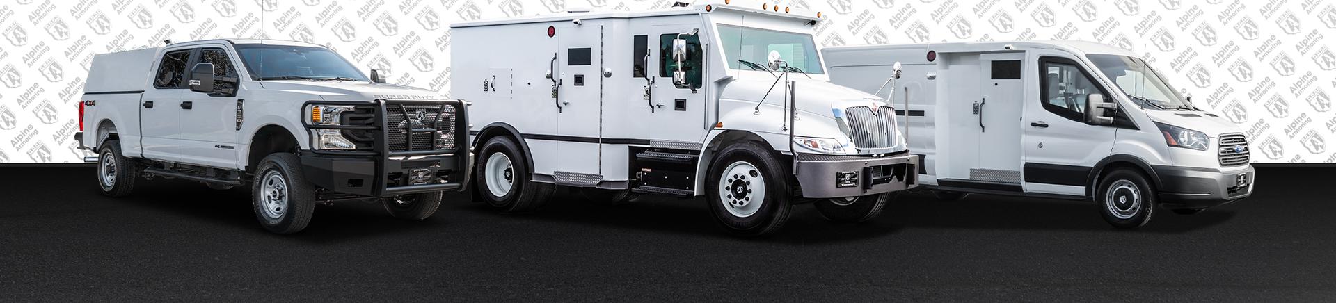 Three white armored vehicles from Alpine Armoring re parked side by side on a black surface . The vehicles vary in size and design, each featuring reinforced structures and secure compartments for transporting valuables.