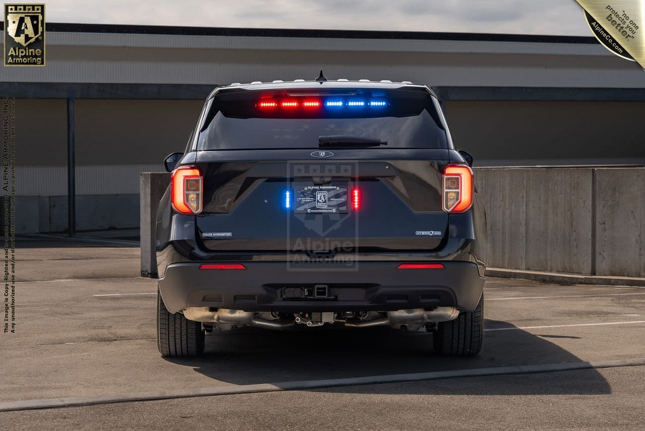 A Ford Explorer Police Protection Vehicle (PPV) with flashing red and blue lights is parked in a rooftop parking structure.