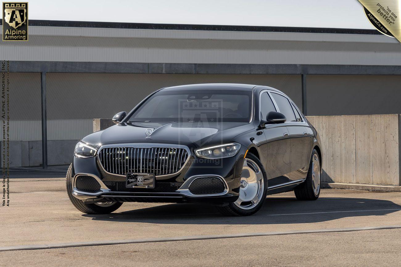 A luxury black bulletproof Mercedes-Benz S 580 Maybach sedanwith a chrome grille is parked in an outdoor setting.