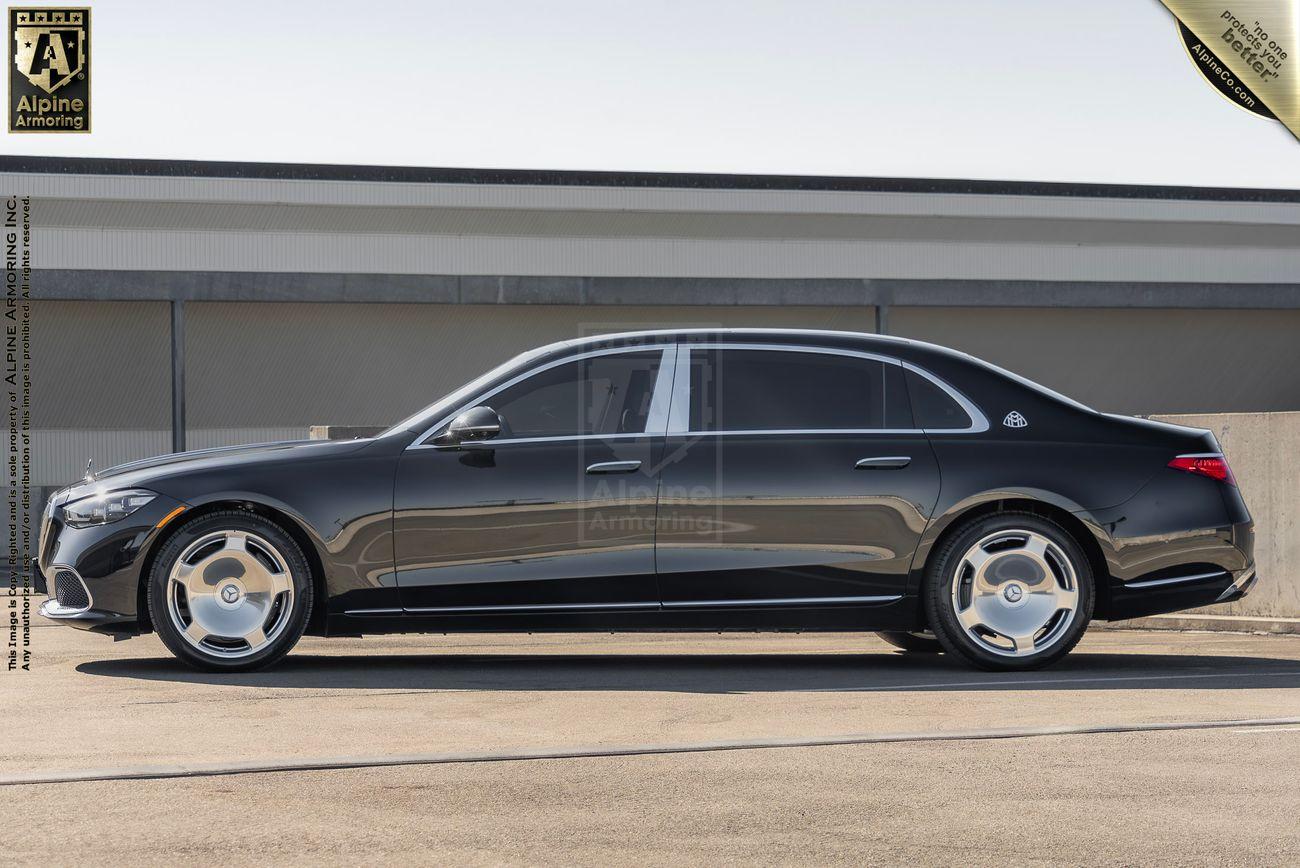 A black armored Mercedes-Benz S 580 Maybach sedan is parked in an outdoor setting against a plain backdrop. The vehicle has a sleek design and large alloy wheels.