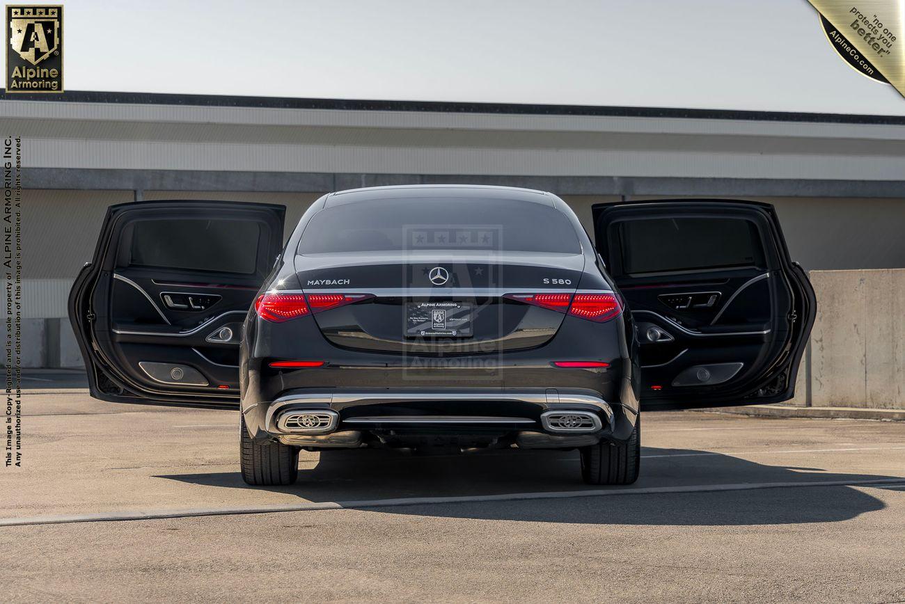 A black armored Mercedes S 580 Maybach sedanwith rear suicide doors open, showcasing the spacious back seats and polished exterior, parked in an urban location.