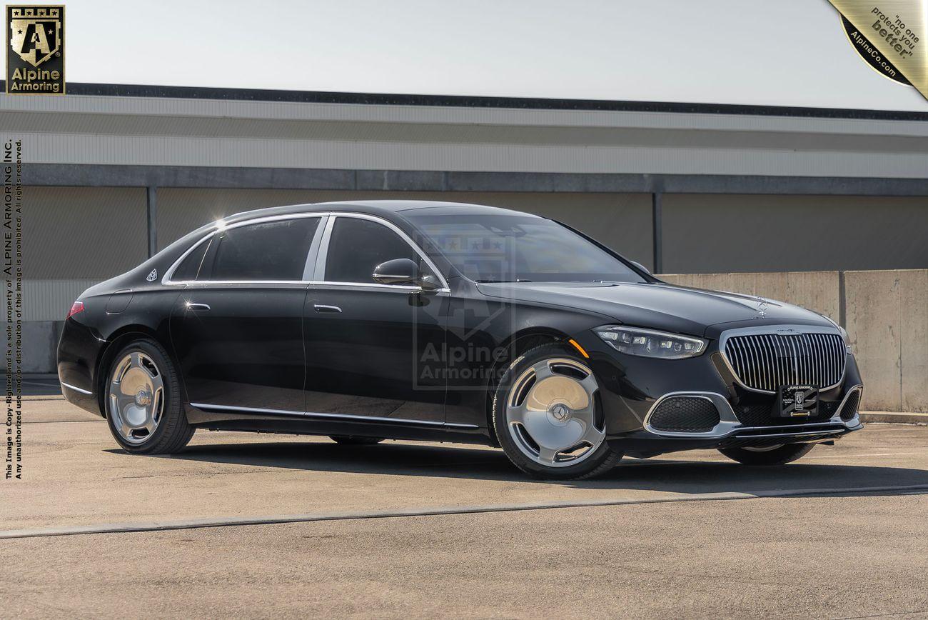 A black luxury Mercedes-Benz S 580 Maybach sedan parked in an outdoor setting, featuring distinctive chrome detailing and branding for Alpine Armoring.