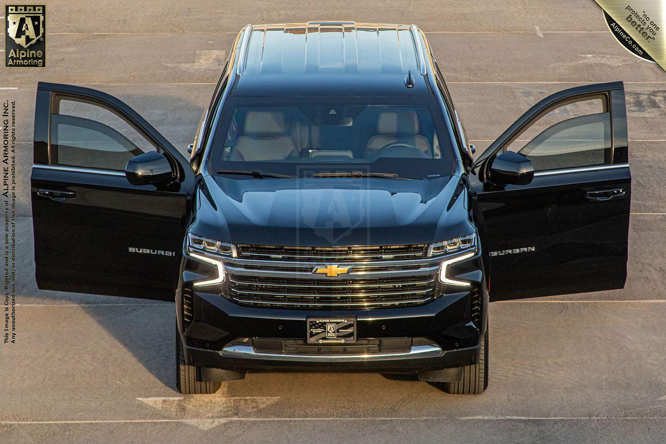 Front view of a black Chevrolet Suburban LT SUV with both front doors open, parked in a lot, displaying its grille and headlights.