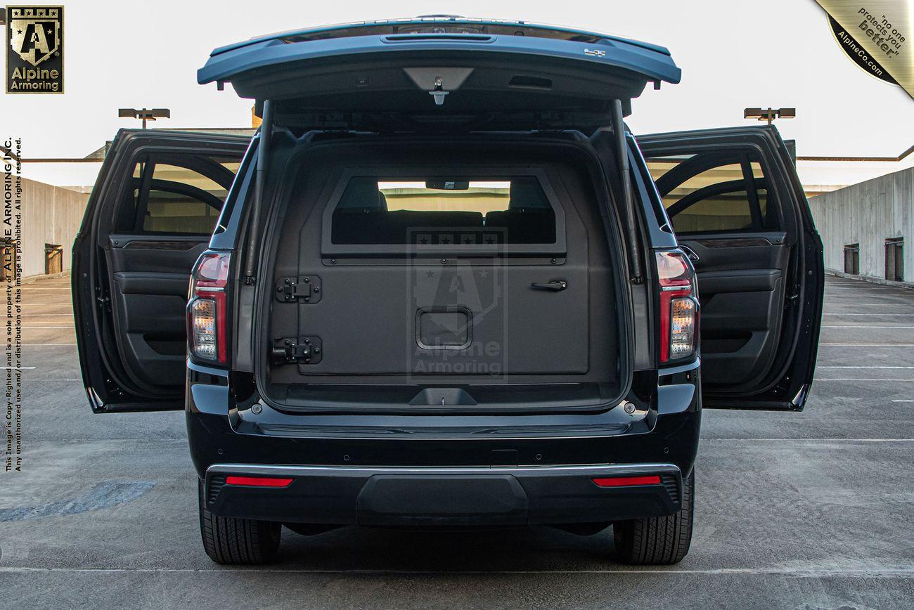 A black armored Chevrolet Suburban LT SUV with all doors open, highlighting its spacious rear cargo area in a parking structure.