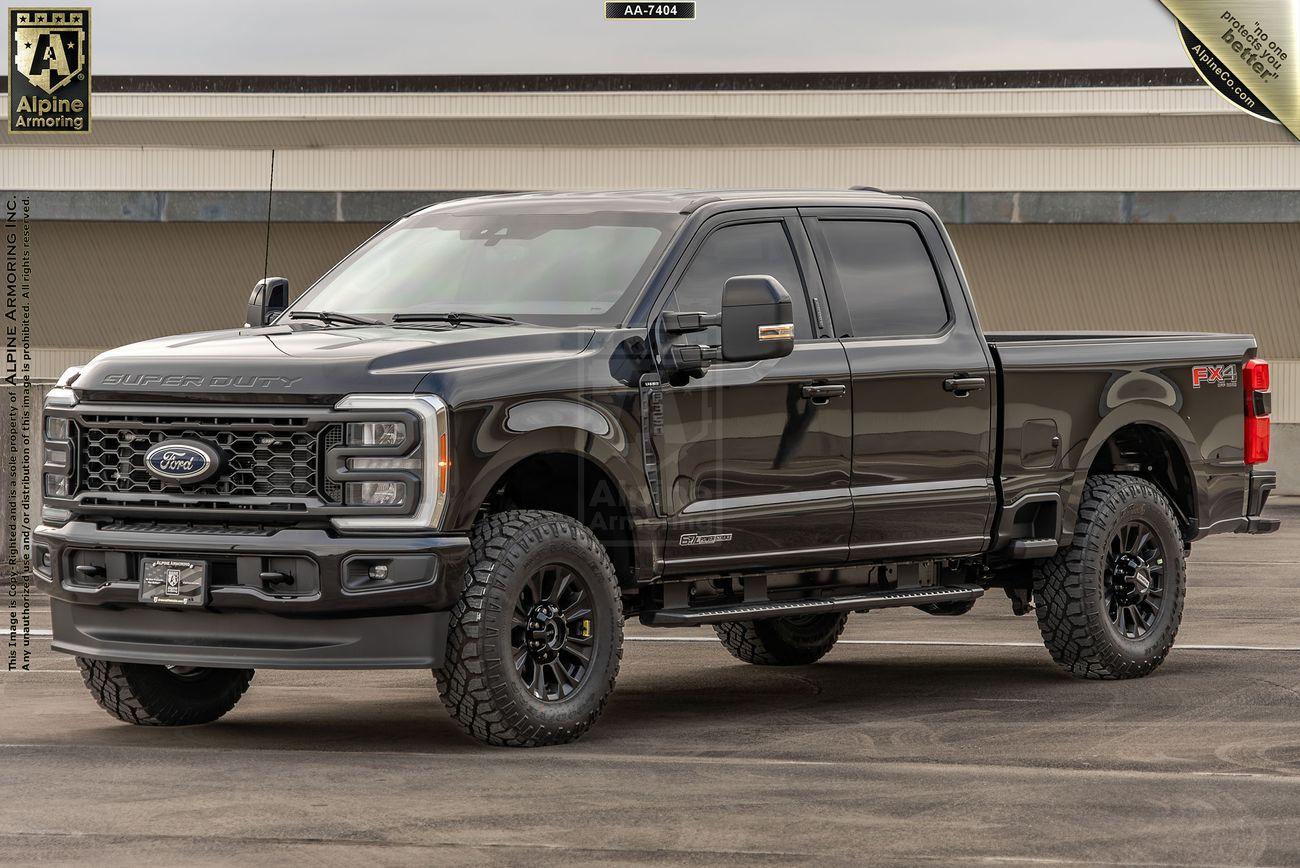 A black, bulletproof Ford F-350 Lariat pickup truck parked on a paved surface in front of a building.