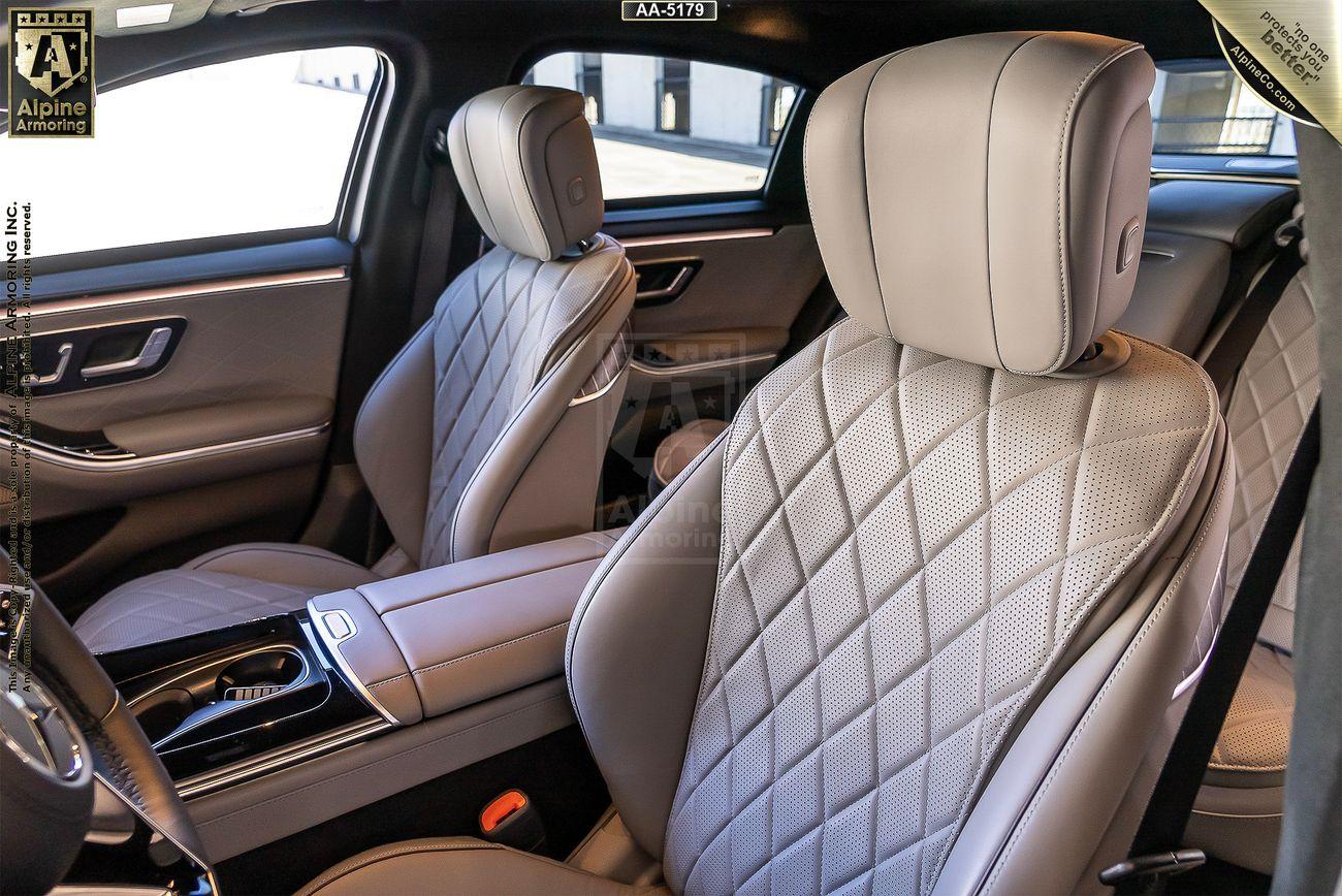 Interior of a black armored Mercedes-Benz S580 S-Class 4MATIC sedan with diamond-stitched leather seats, a sleek center console, and modern door panels.