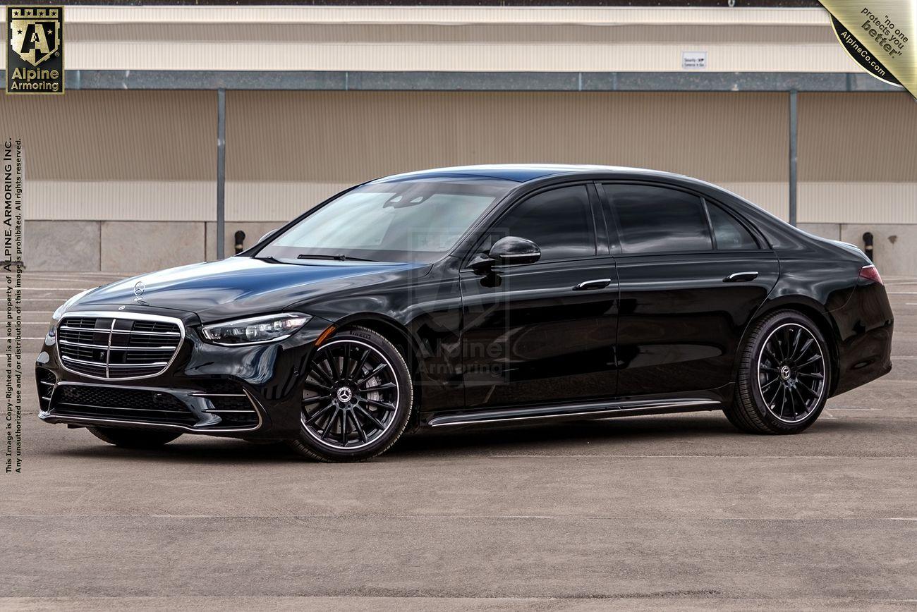 A black Mercedes-Benz S580 luxury sedan is parked on a concrete surface in front of a beige building with a closed gray garage door.