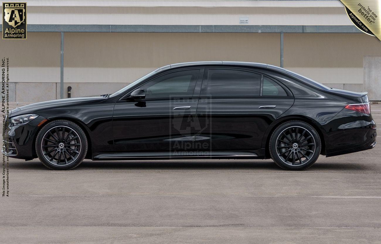 A black luxury armored Mercedes-Benz S580 sedan is parked in front of a beige and white wall. The car has dark tinted windows and black rims. The logo "Alpine" appears at the top left corner of the image.