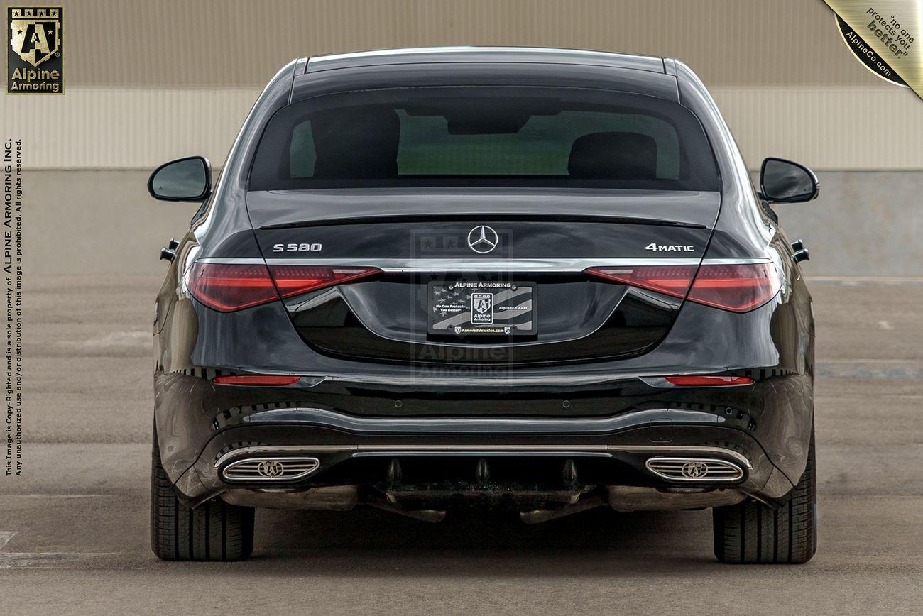 Rear view of a black Mercedes-Benz S580 AMG sedan parked on a concrete surface, showcasing its taillights, exhaust pipes, and the Mercedes emblem.