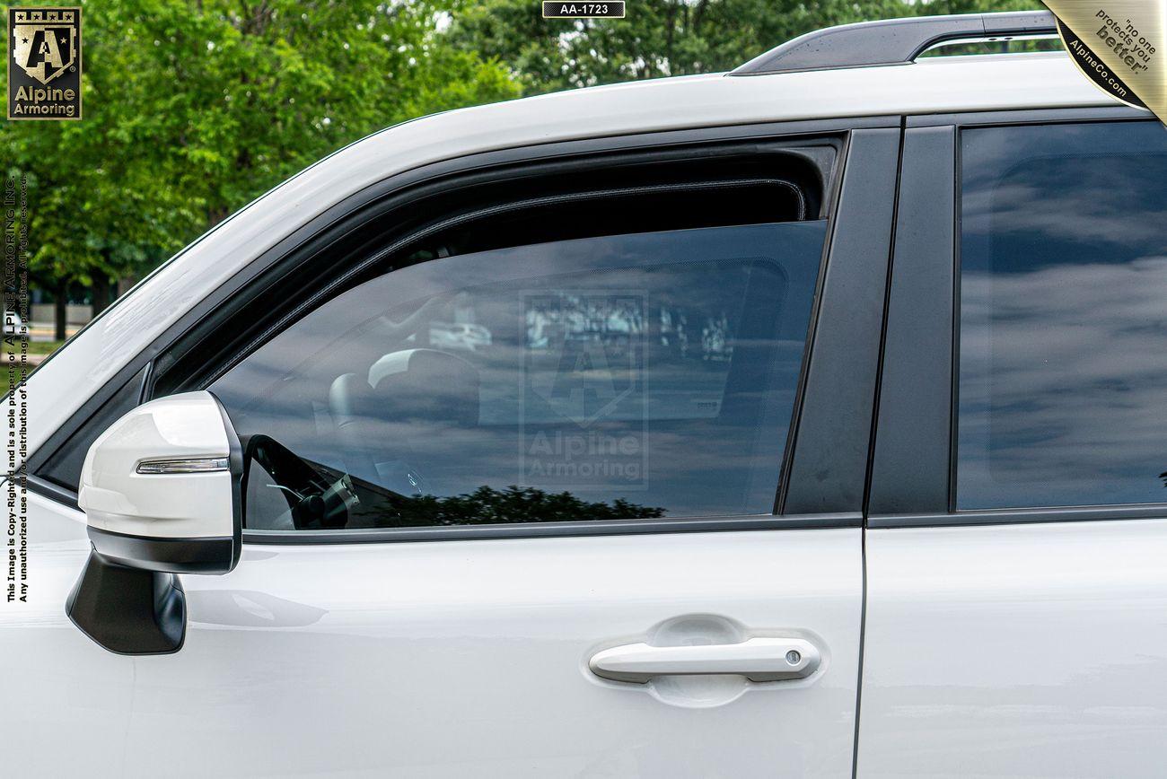 Side view of a white Toyota Landcruise with black trim and tinted windows. The reflection of the sky and trees is visible on the windows. 