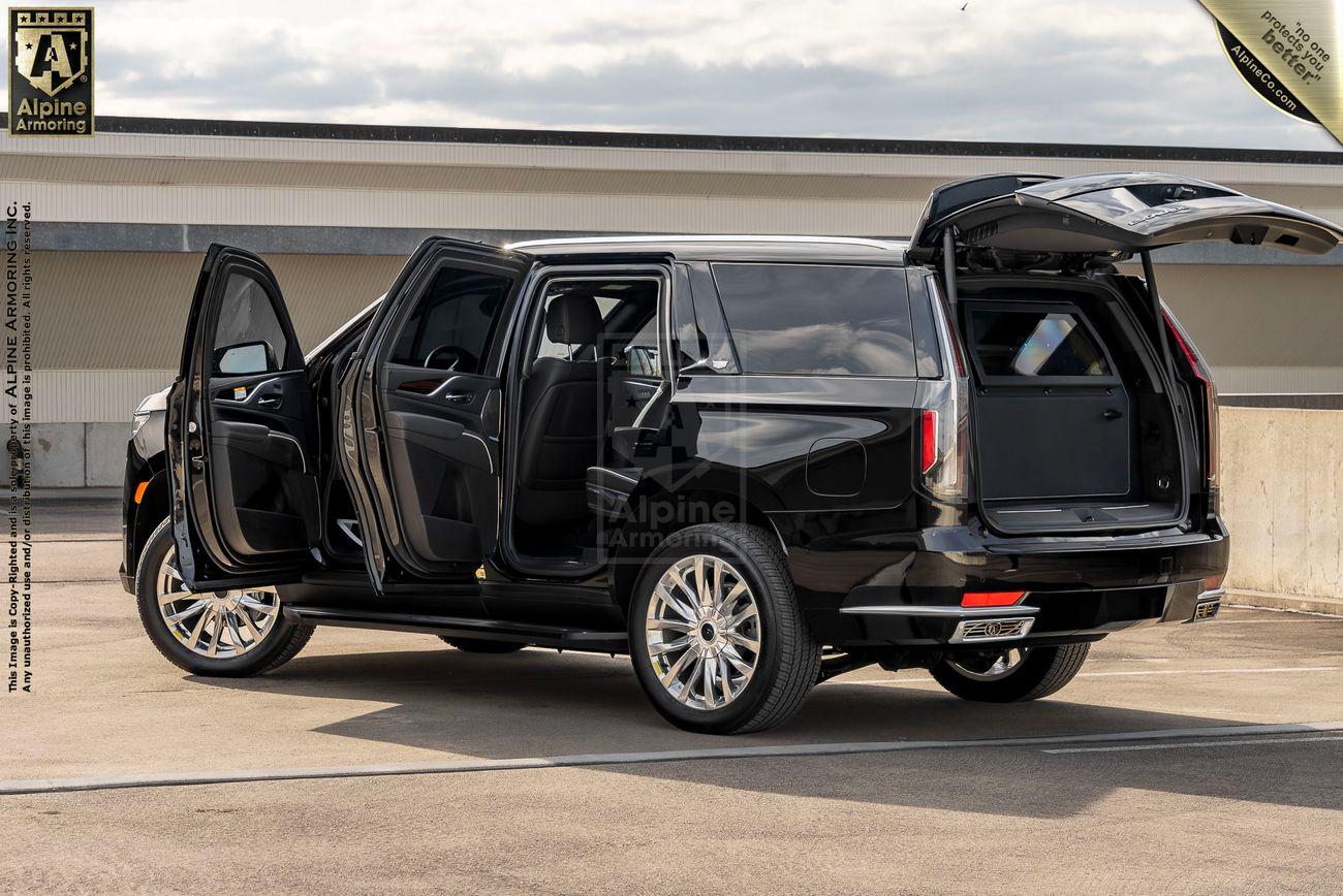 A black bulletproof Cadillac Escalade luxury SUV with all four side doors and the rear hatch open, showcased in an outdoor setting.