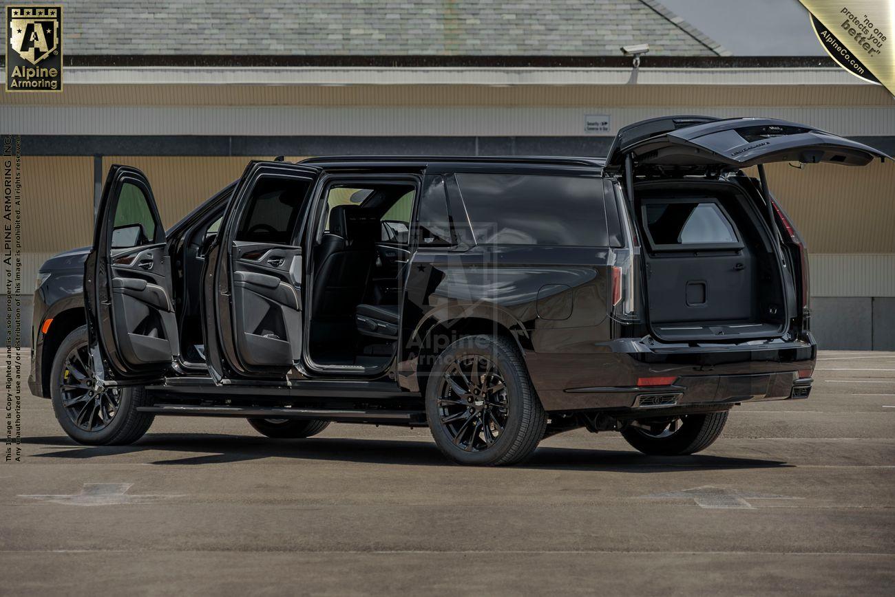 A black bulletproof Cadillac Escalade ESV SUV with all doors and the rear hatch open, showcasing a spacious interior and cargo area in an outdoor setting.