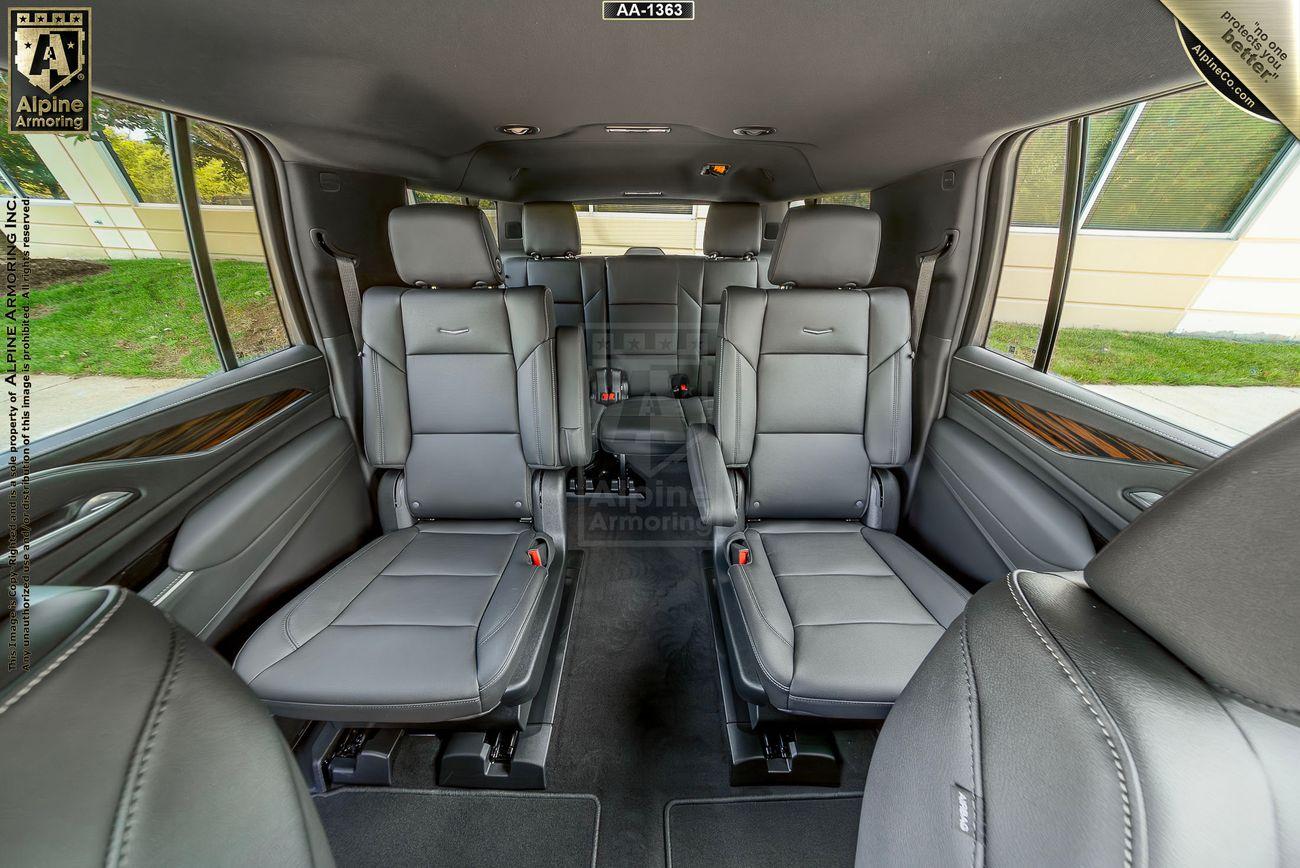 Interior of a black Cadillac Escalade ESV Luxury SUV featuring gray leather seats arranged in a spacious, two-row configuration. The image highlights ample legroom and sleek design.