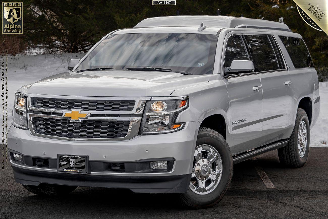 Silver Chevrolet Suburban 3500HD LT VIP Limo parked on a snow-dusted asphalt surface with trees in the background.