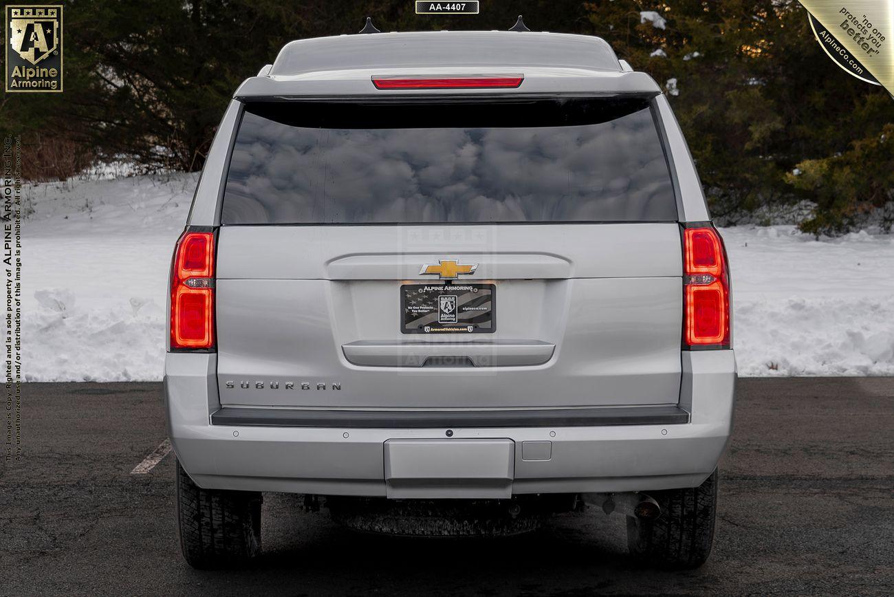 A white Chevrolet Suburban 3500HD LT VIP Limo is parked on an asphalt surface with snow in the background. The rear of the vehicle is visible, showing taillights, a license plate, and the Chevrolet logo.