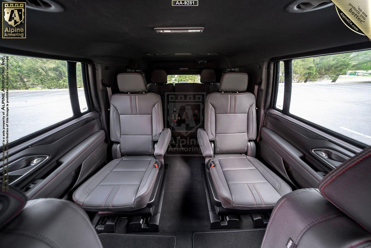 Interior of a luxury, armoured Chevrolet Suburban RST SUV featuring four leather bucket seats and large windows.