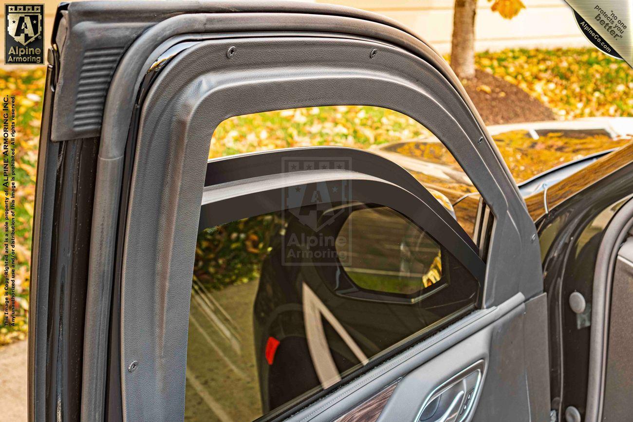 A Chevrolet Tahoe SUV door with an open, bulletproof glass window is shown, displaying the detailed interior edge around the window frame.