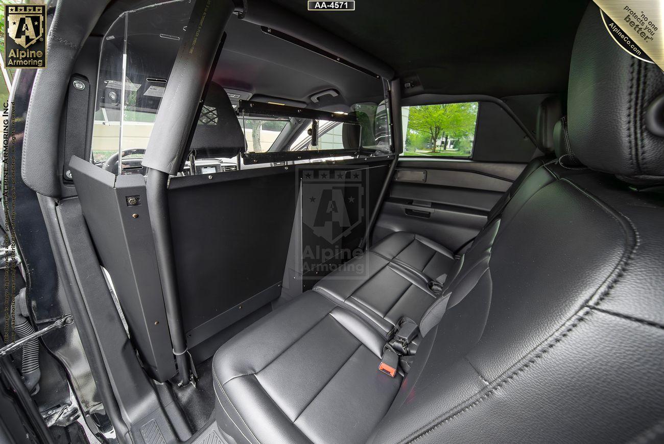 Interior view of a bulletproof PPV showing the backseat area equipped with a partition separating the front and rear sections, designed for security purposes. Black leather seats and a window are visible.