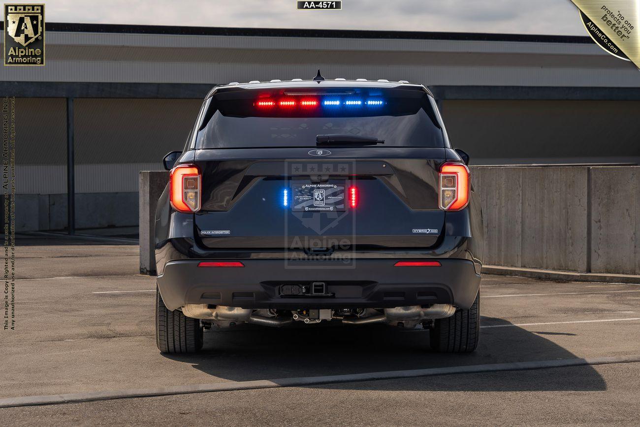 The rear view of a black Ford Explorer Police Protection Vehicle (PPV) SUV is shown. The vehicle is parked on a concrete surface near a building.