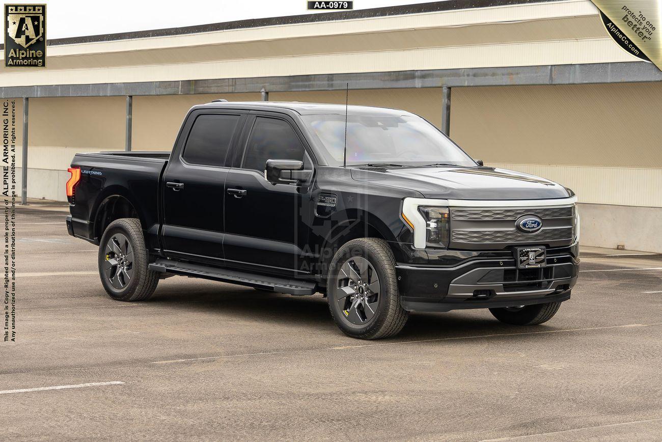 Front-right view of a black armored Ford Lightning truck. Setting is in a parking lot.