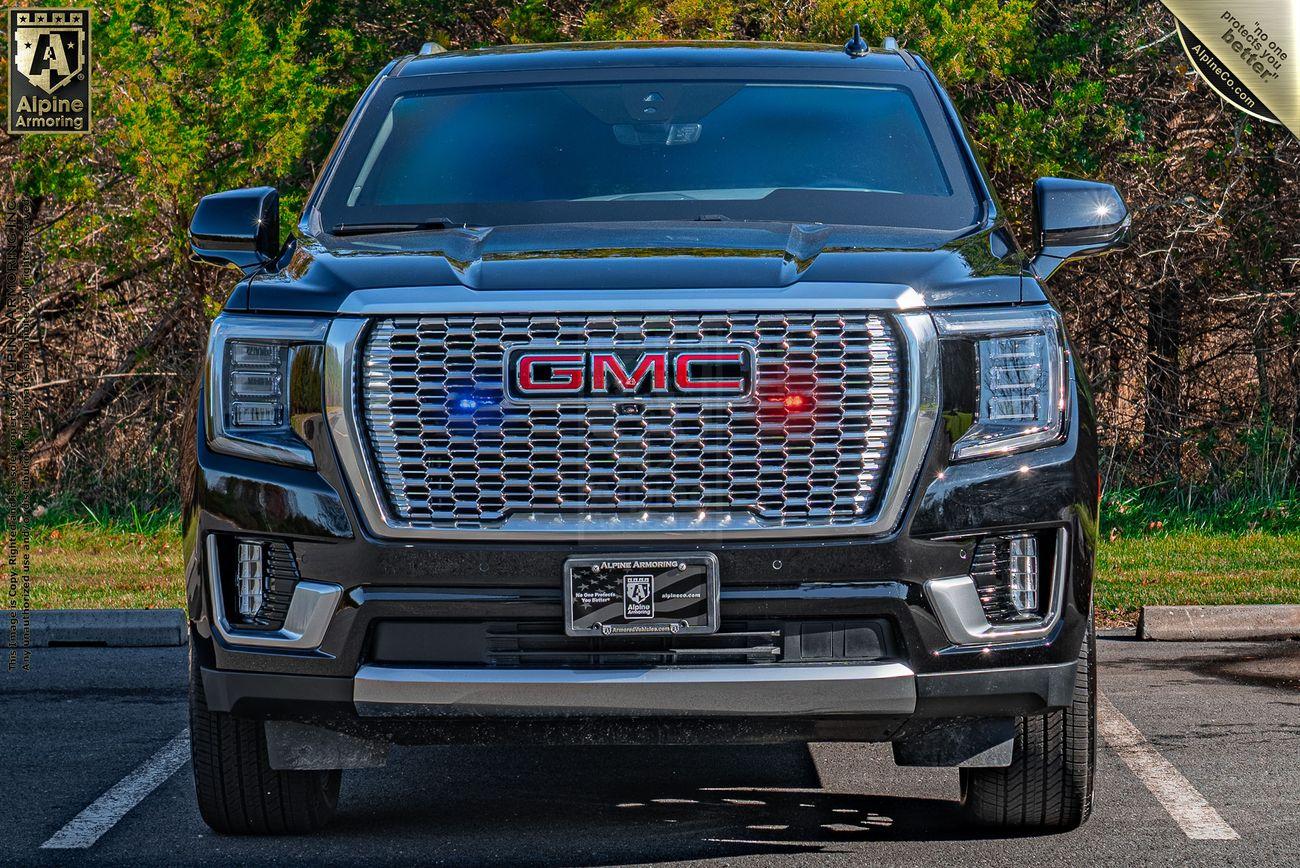 Front view of a black GMC Yukon Denali with a large chrome grille, parking lights, and a parking lot setting.