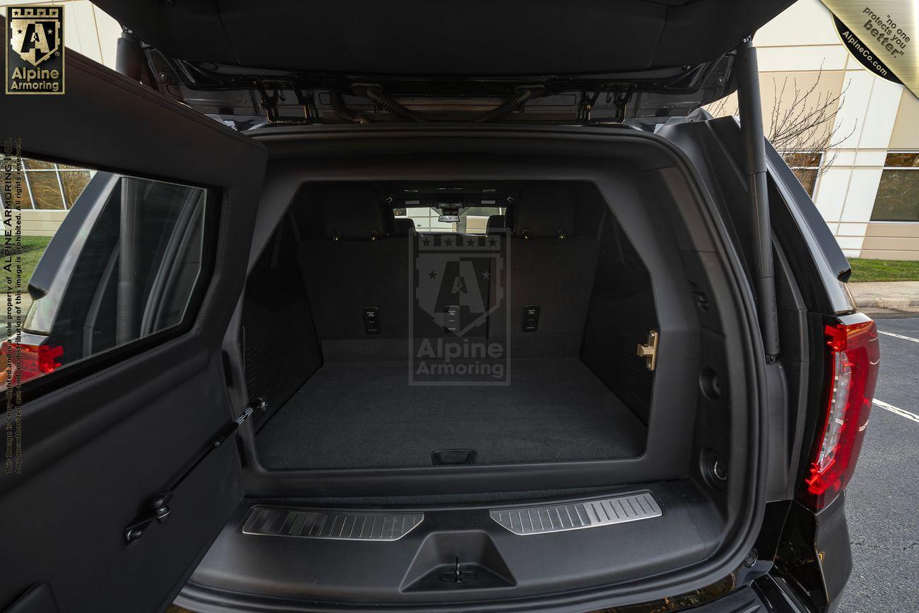 An empty armored GMC Yukon Denali XL SUV 's rear cargo area with open rear doors, showing a spacious and reinforced interior.