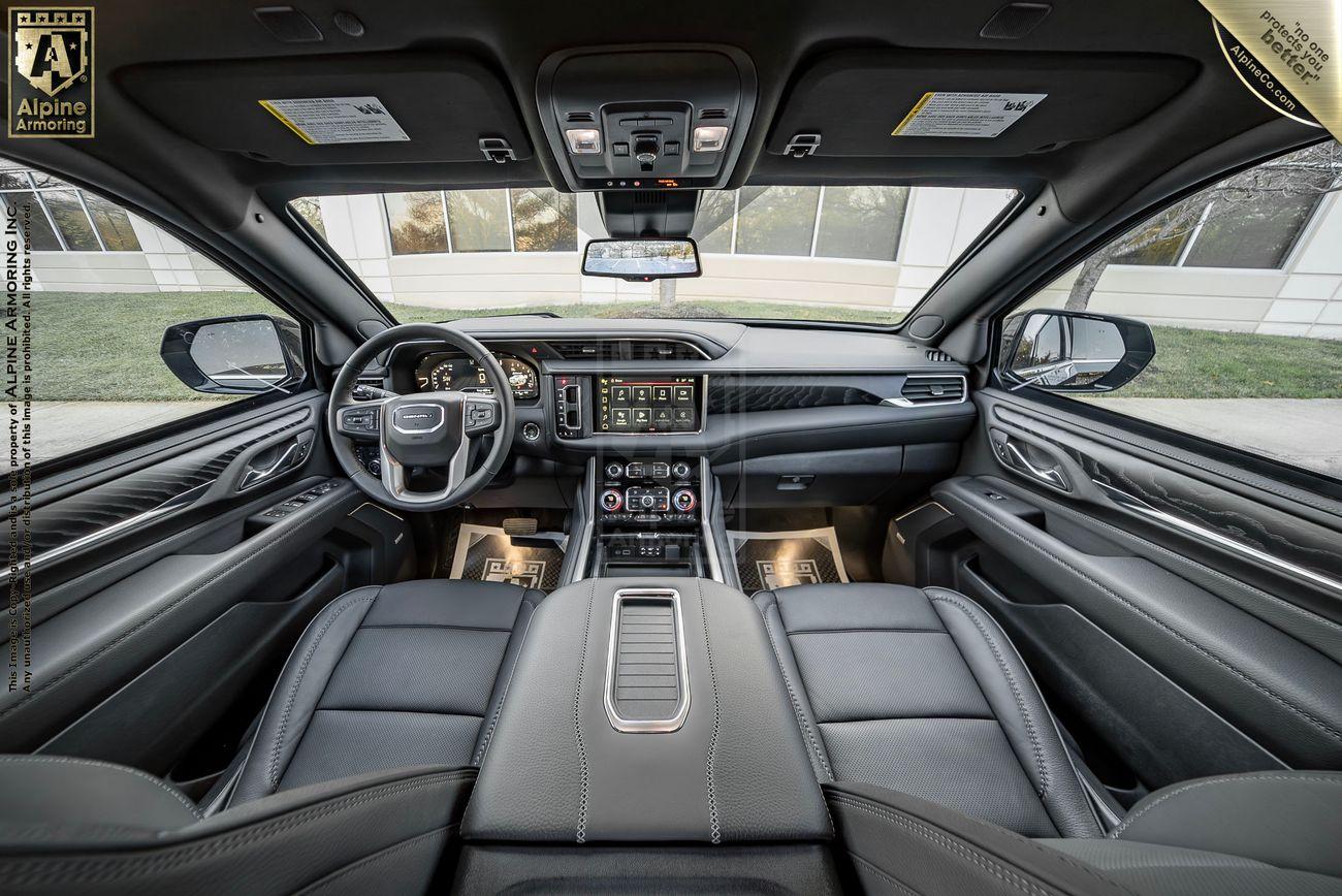 An armored GMC Yukon Denali XL interior featuring a sleek dashboard with digital displays, leather seats, and a panoramic sunroof.