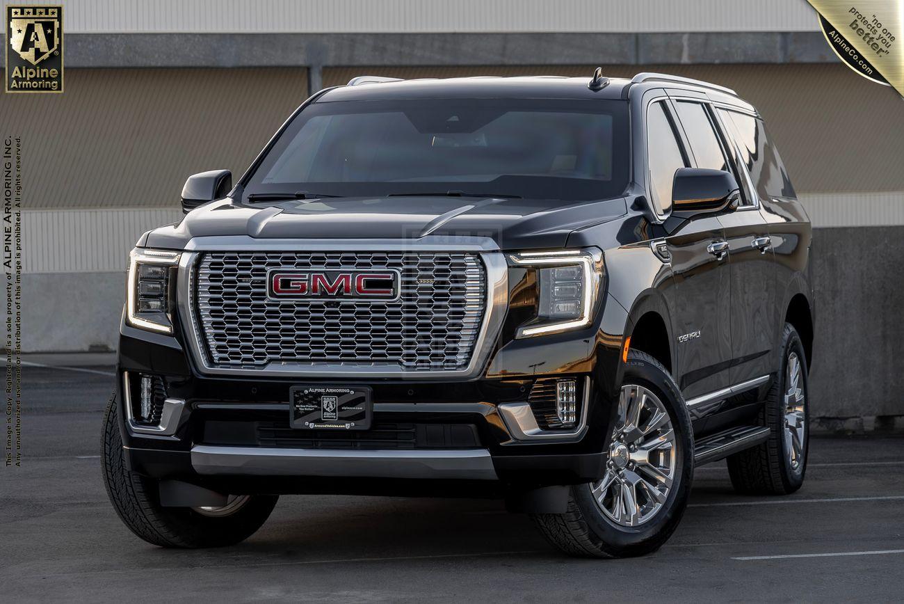 A black bulletproof GMC Yukon Denali XL SUV is parked in a concrete area, showing its front and side profile.