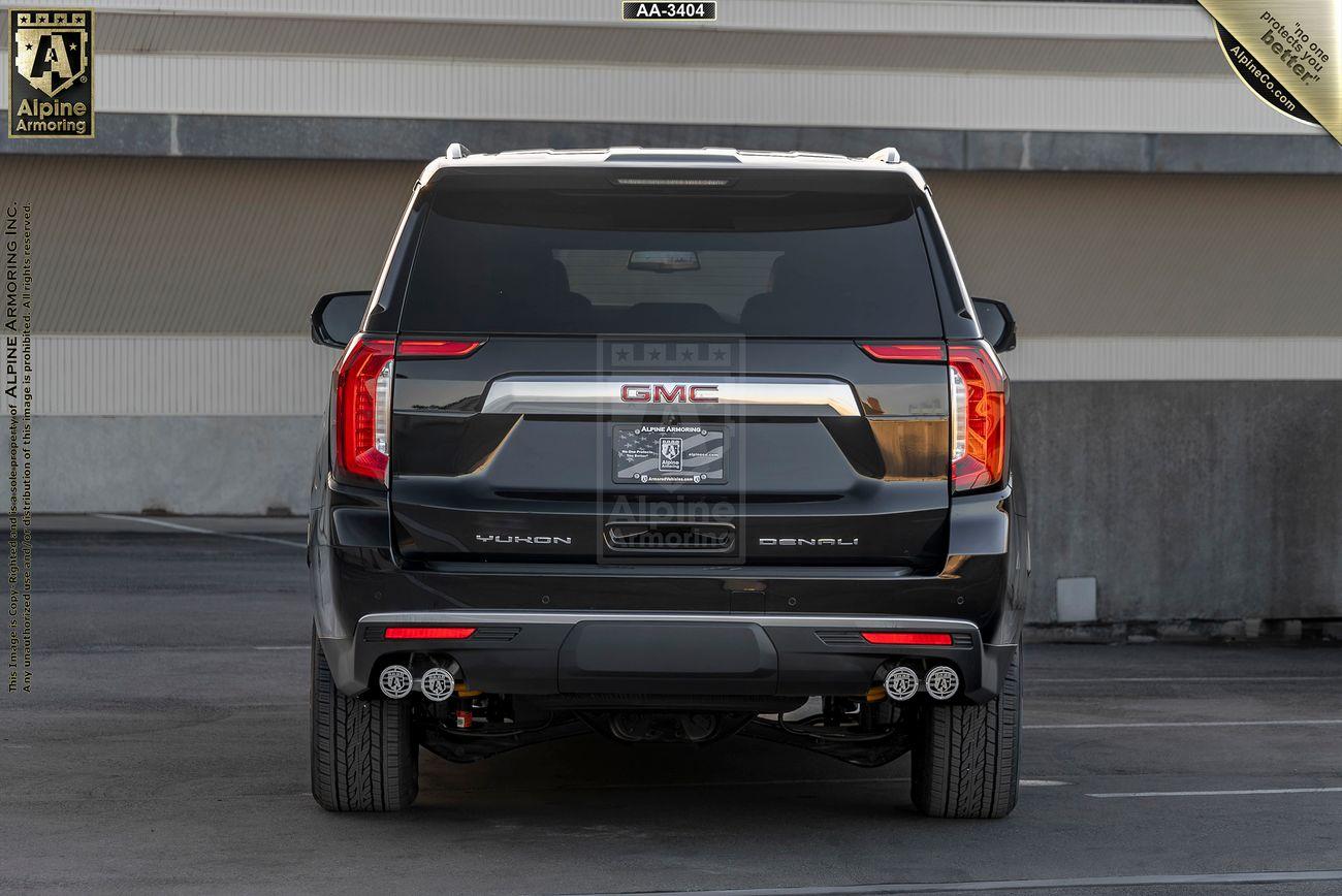 Rear view of an black armored GMC Yukon Denali XL with GMC branding. The setting is a parking lot.