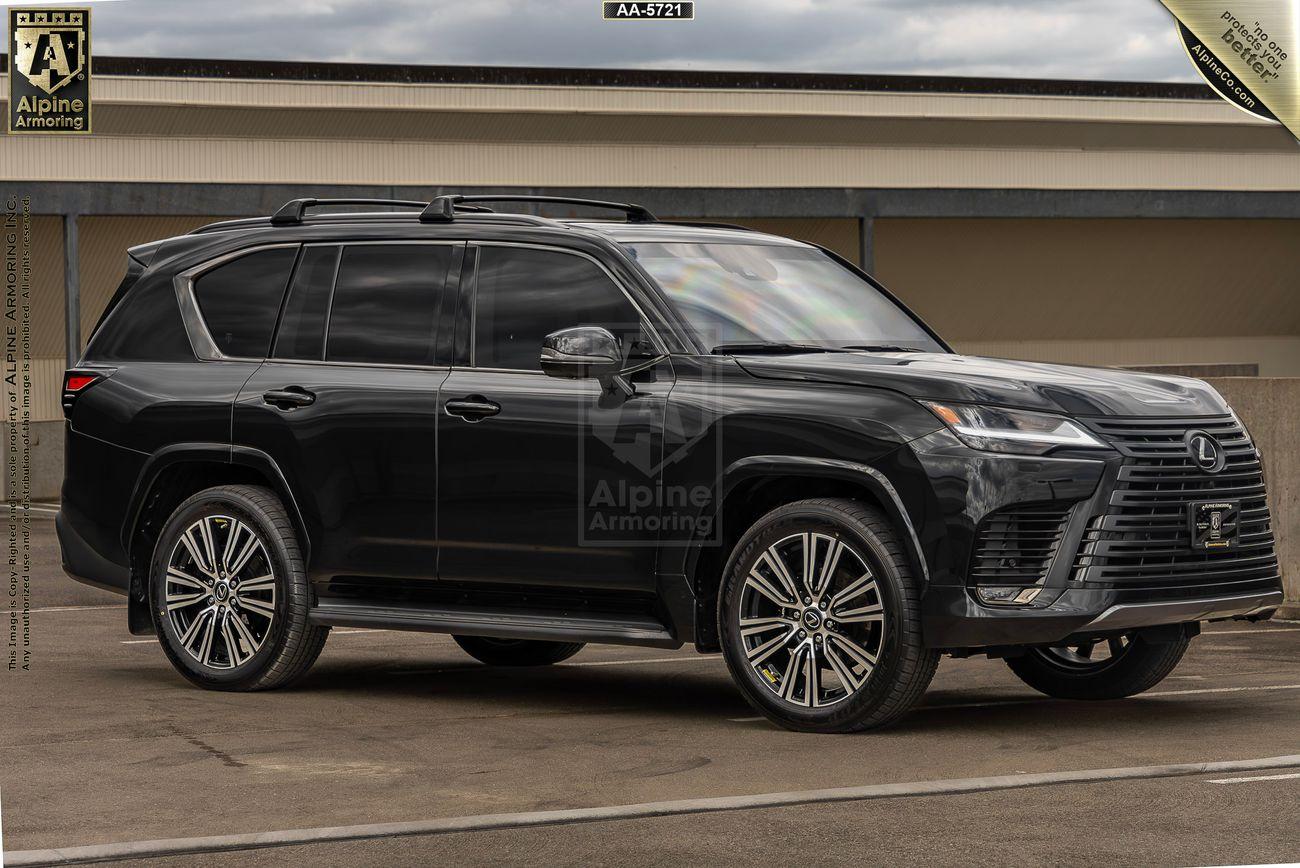 A black Lexus LX600 Luxury SUV with tinted windows parked in front of a building on a cloudy day, displaying the Alpine Armoring logo on its side.