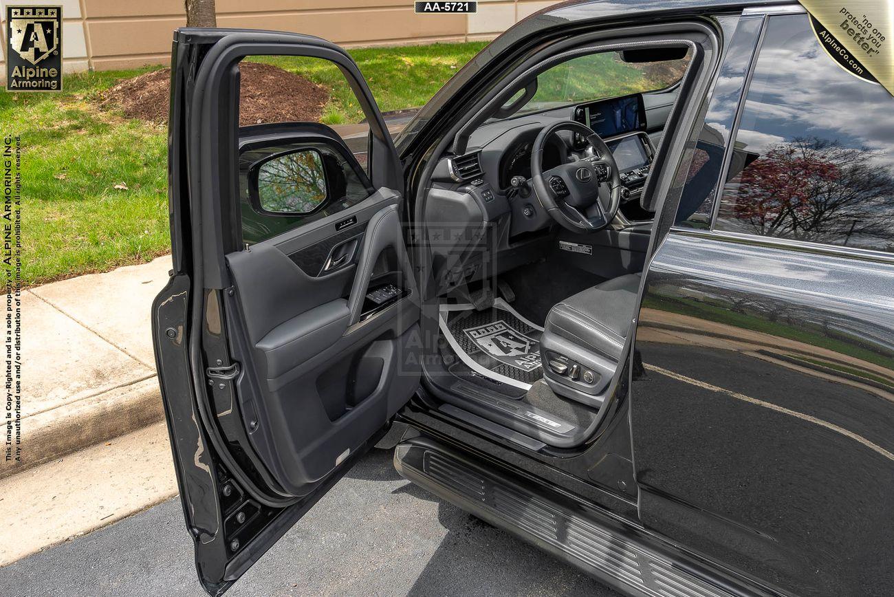 The driver's side door of a black bulletproof Lexus LX600 Luxury SUV open, revealing the interior with the seat, steering wheel, dashboard.