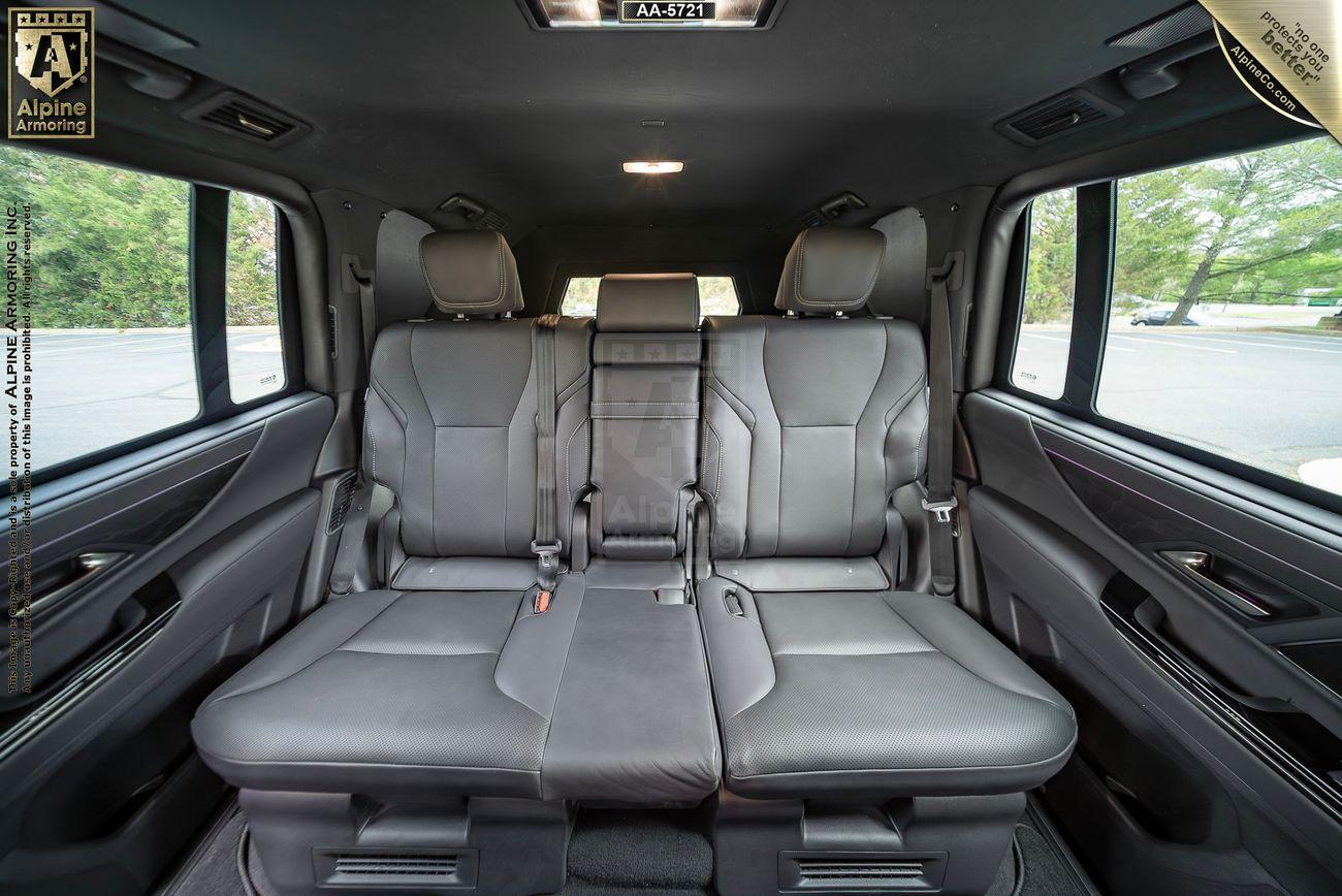 The interior of a black armored Lexus LX 600 Luxury SUV from Alpine Armoring, parked in an outdoor setting.