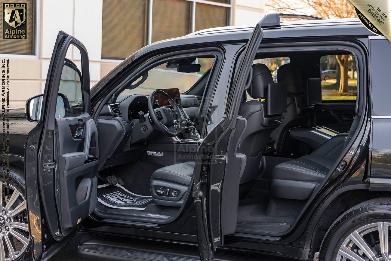 The left side of armored Lexus LX600 Ultra Luxury with both driver side doors open.  The vehicle is parked next to an office building.