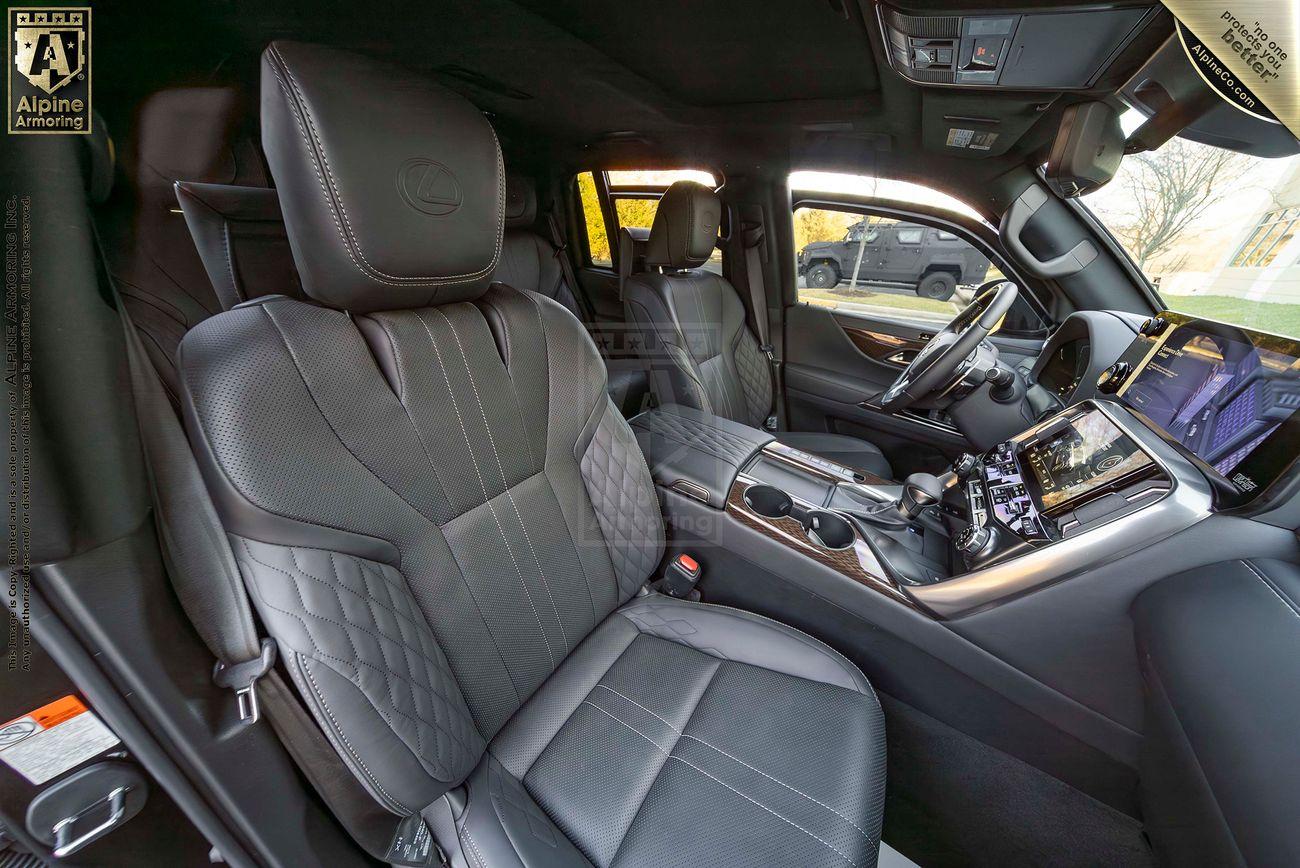 Interior of an armored GMC Yukon Denali XL with black leather seats, a modern dashboard, a touchscreen display, and silver accents. The front passenger and driver seats are both visible.