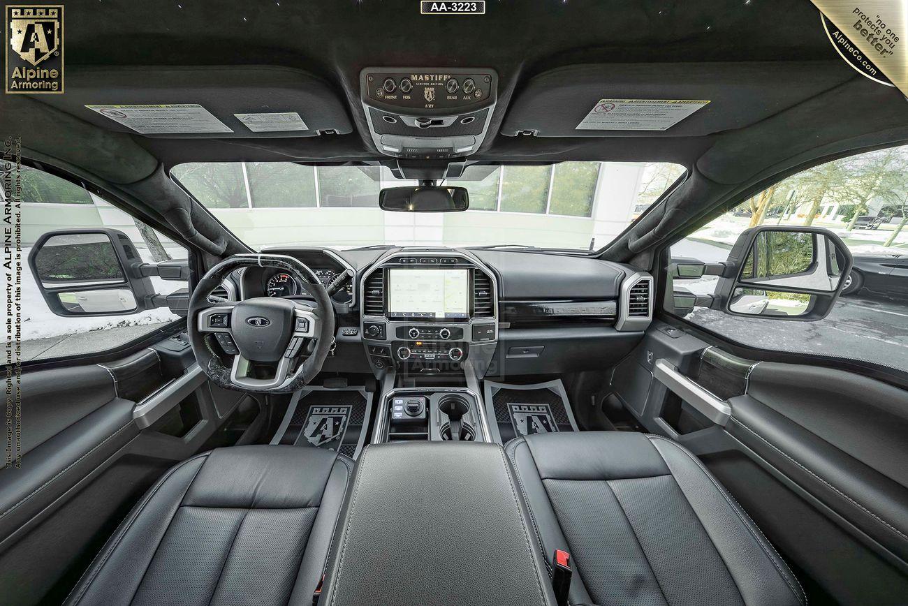 Interior of a Mastiff  featuring a sleek dashboard, large central touchscreen display, multiple control buttons, leather seats, and a panoramic sunroof with a view of the exterior through the windows.