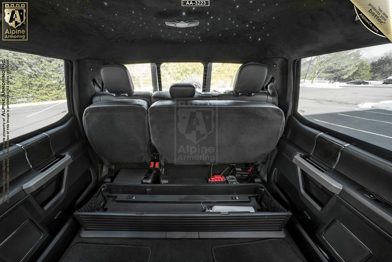 Interior view of a Mastiff showing the spacious rear compartment with seats folded up, exposing a storage area. The ceiling features mounted lights, and the side windows provide natural light.