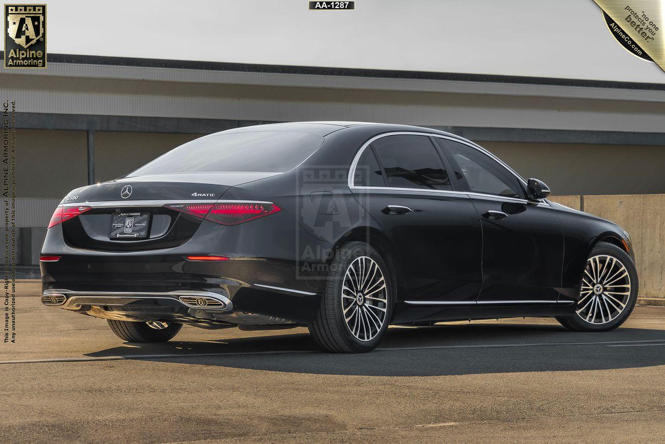 A black armored Mercedes-Benz S580 Executive sedan with tinted windows parked in an outdoor area. The back of the vehicle is facing the camera, showcasing its tail lights and rear design.