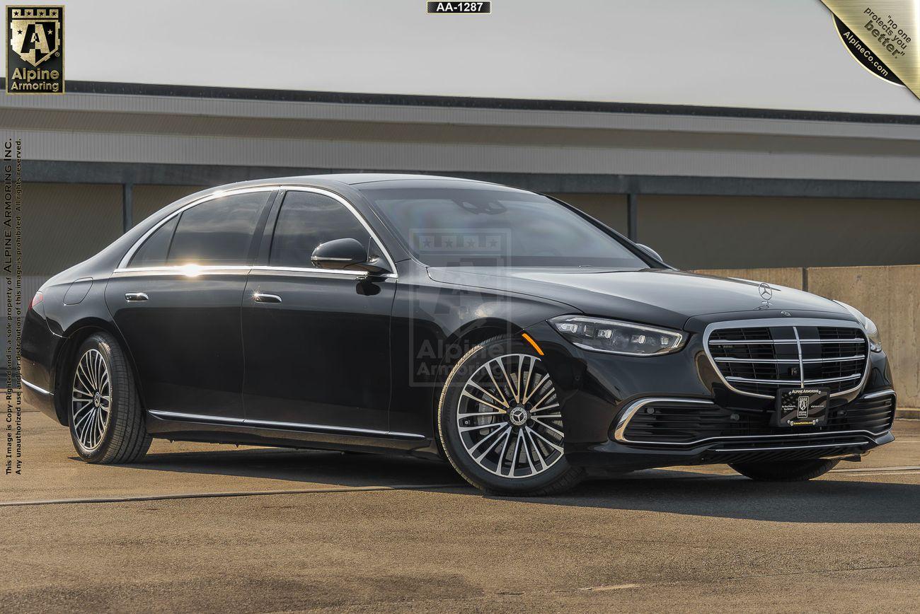 A black armored Mercedes-Benz S580 Executive sedan with polished chrome accents is parked outside a building on a sunny day.