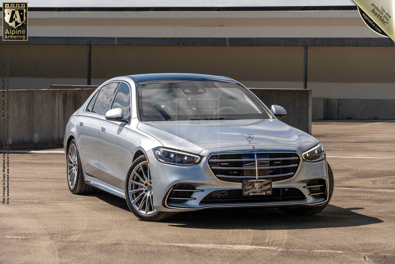 A silver Mercedes-Benz S580 sedan is parked in an outdoor setting on a concrete surface near a building.