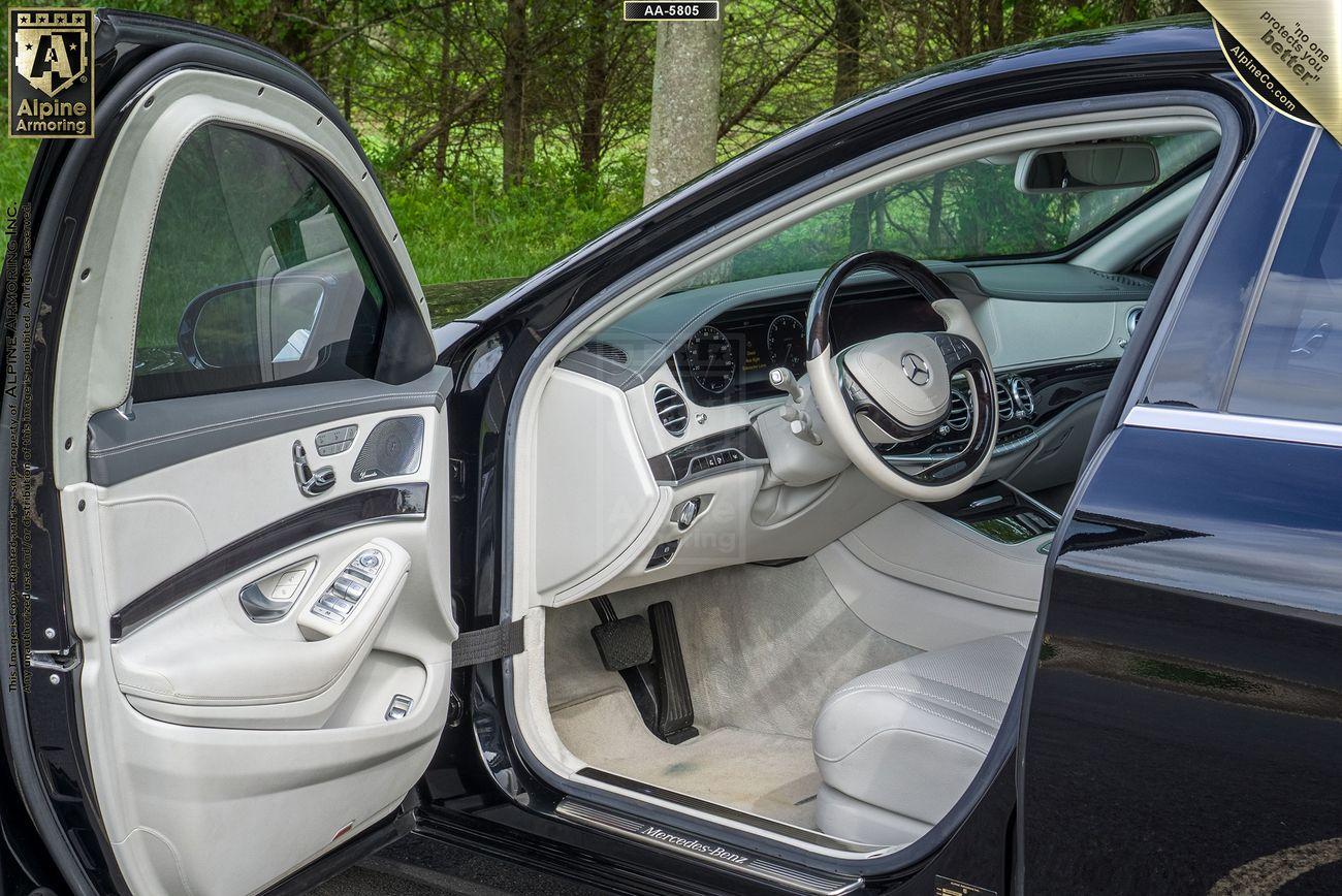 Interior view of a luxury Mercedes-Benz 560 with the driver-side door open, showcasing a white leather interior, steering wheel with a logo, and various controls on the door panel.