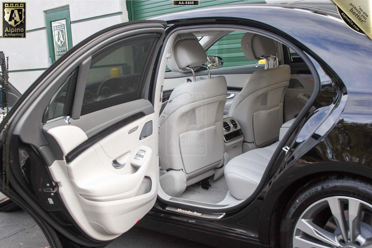 Image showing the interior of a Mercedes-Benz 560 with both front and rear doors open, revealing light-colored leather seats and clean upholstery. The vehicle appears to be in a garage or detailing facility.