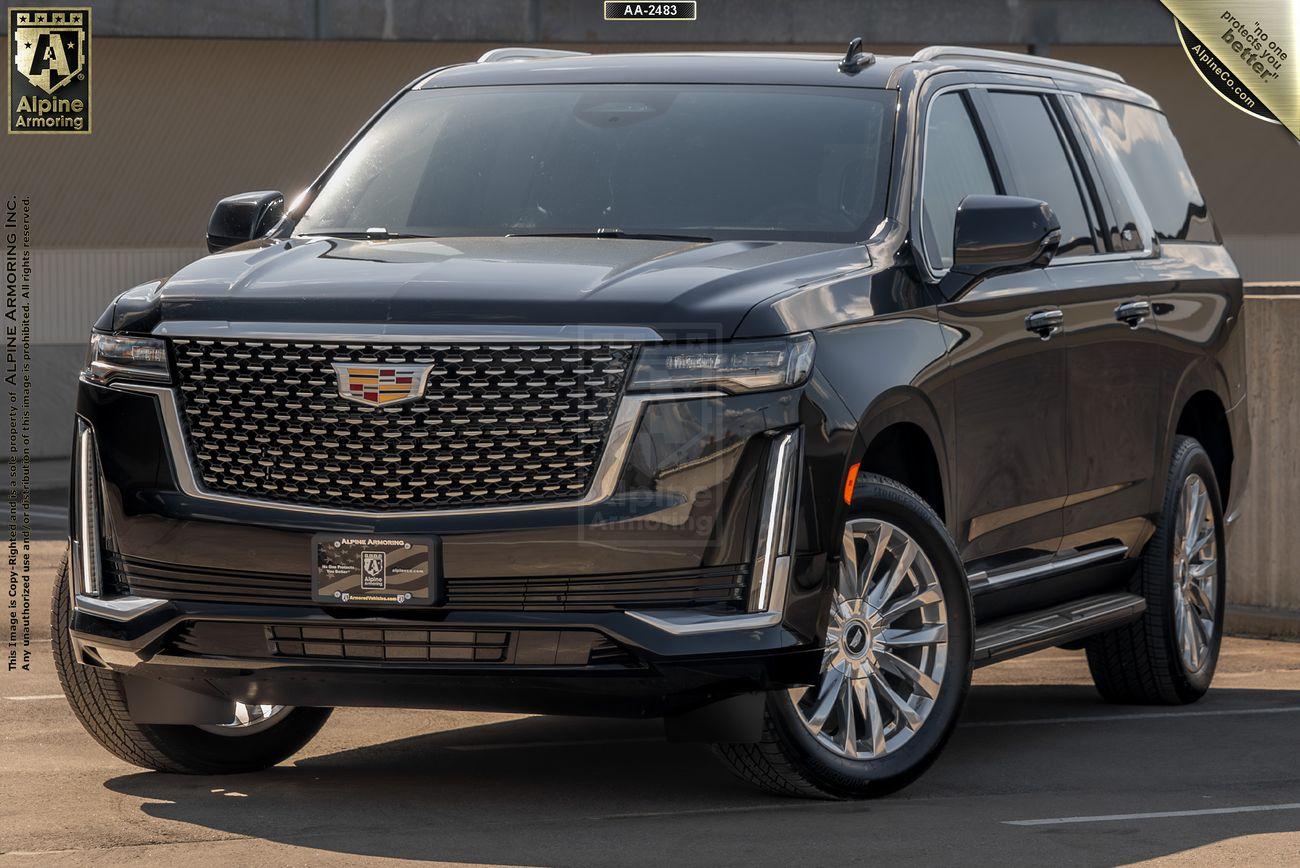 A black, armored Cadillac Escalade ESV Premium LuxurySUV parked in an outdoor lot, showcasing its front and side view. The vehicle features a large, distinctive grille and chrome accents. Branding and dealership information are visible.