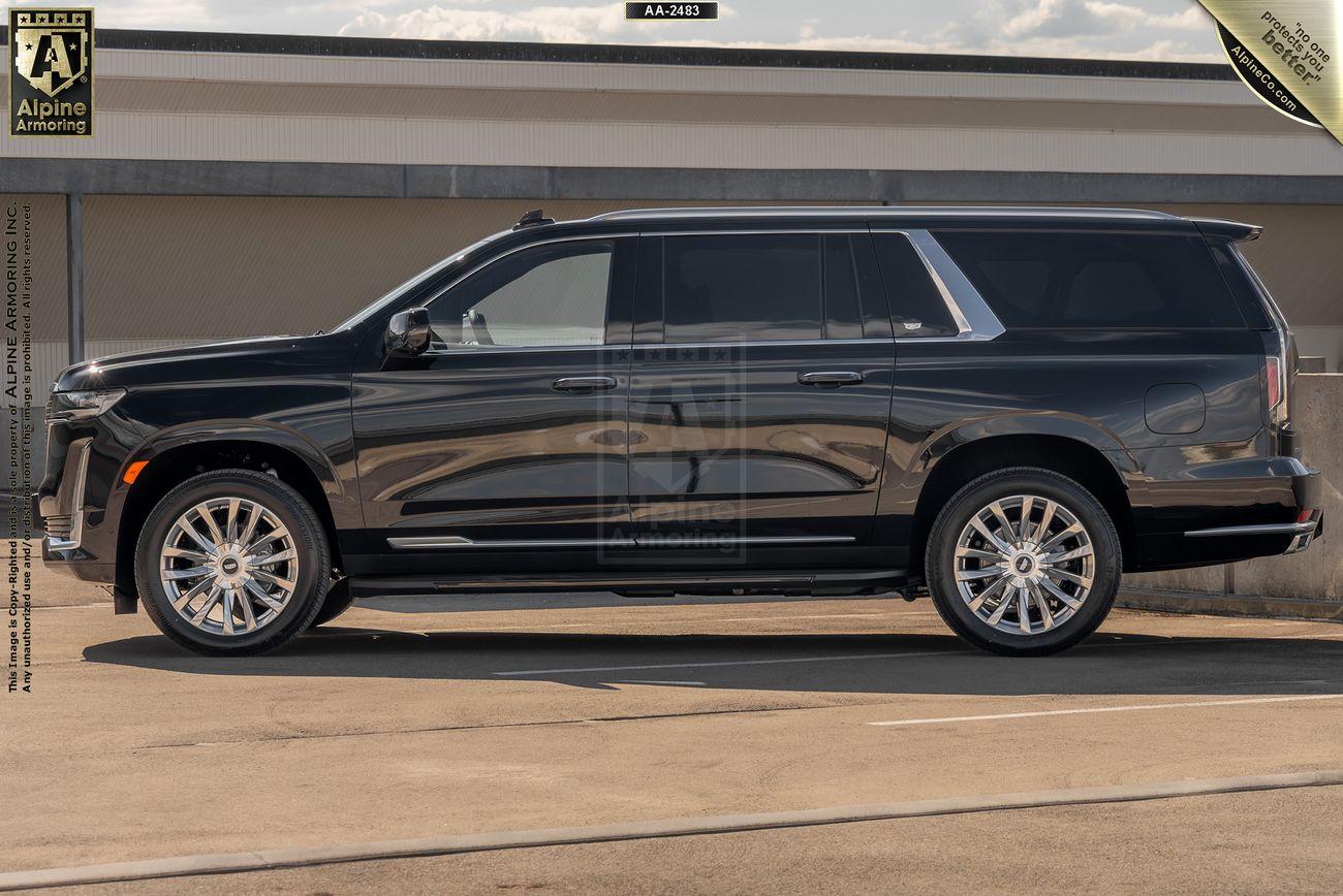 A black armored Cadillac Escalade ESV Premium Luxury is parked outdoors with a clear view of its side profile. The vehicle has large wheels and tinted windows. An Alpine Armoring logo and certification badges are visible on the image.