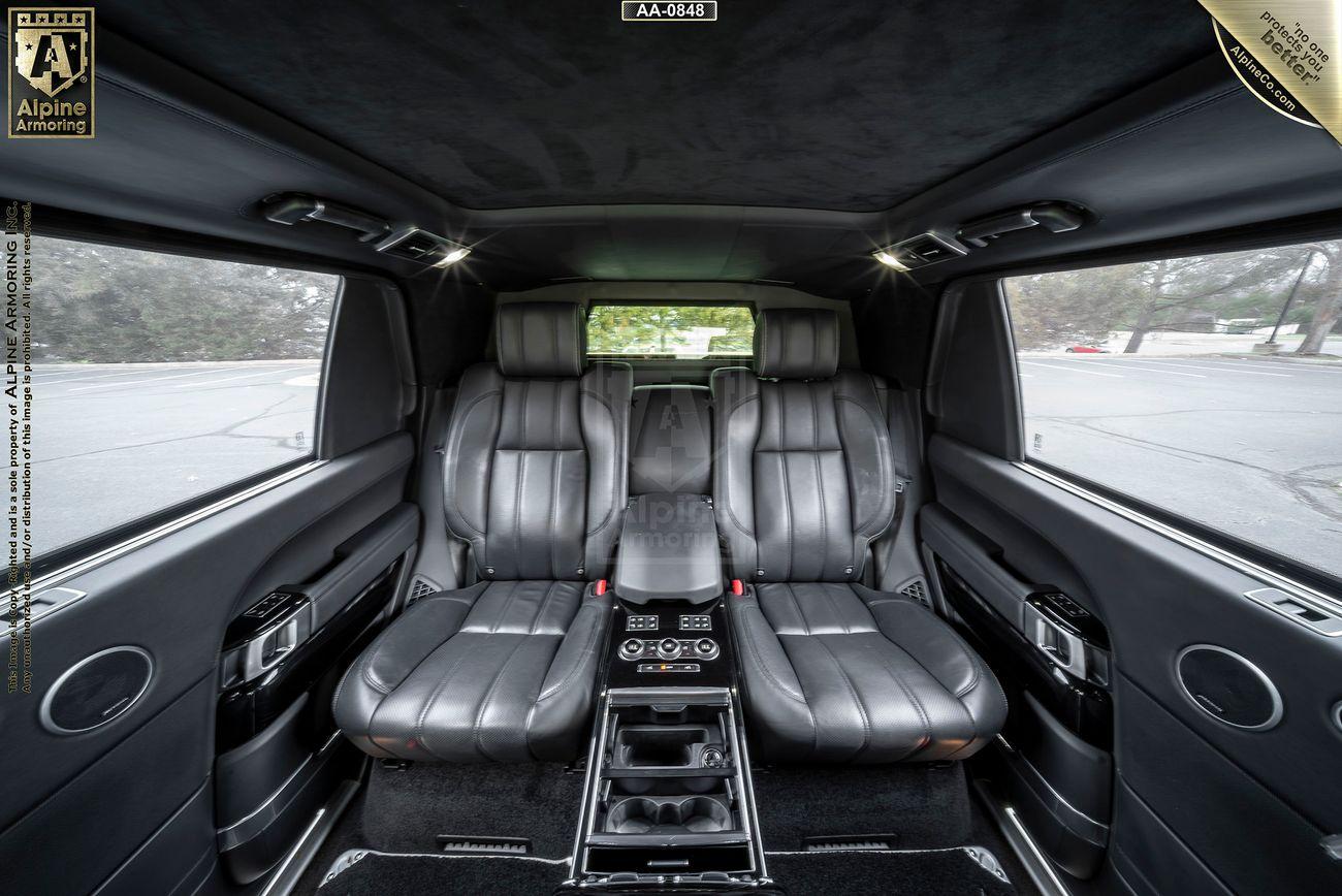 Luxurious car interior featuring black leather seats, a central console with controls, and side windows showcasing an outdoor view.